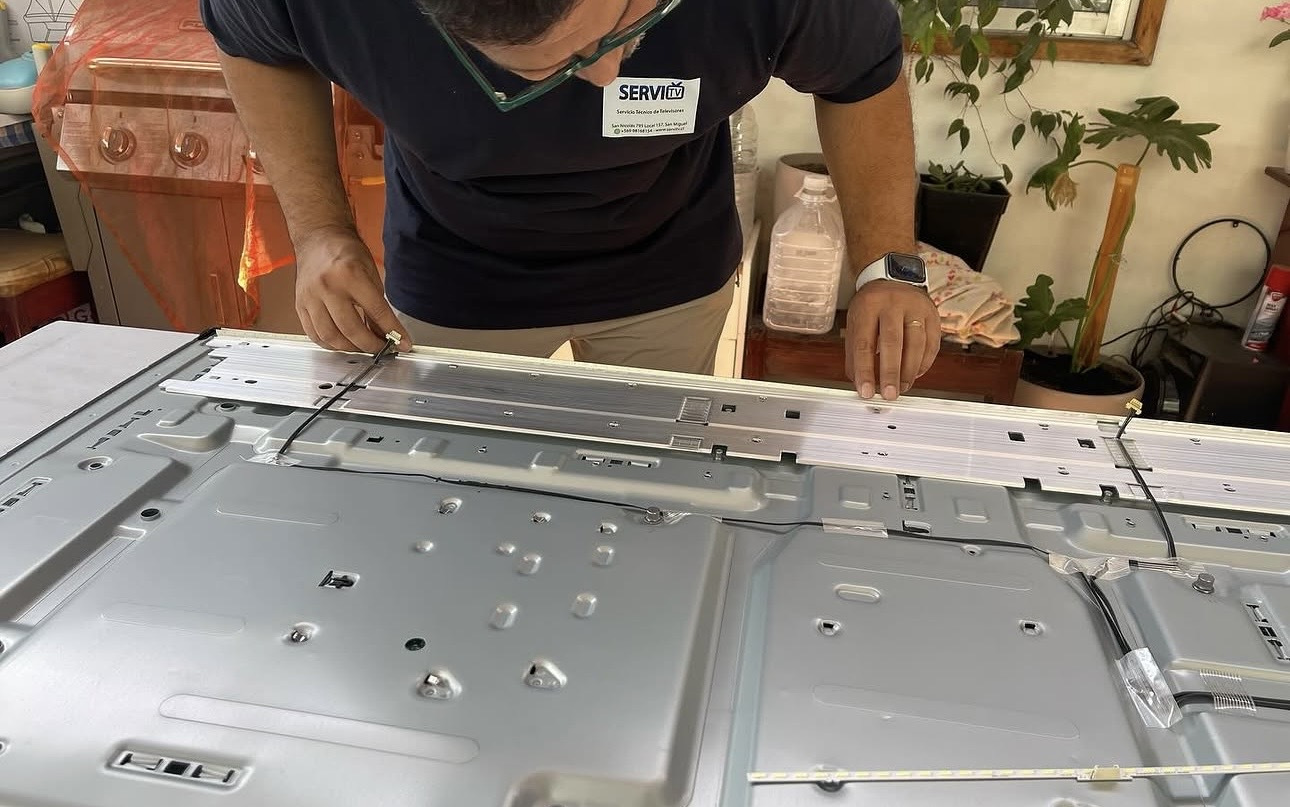 Técnico reparando un televisor a domicilio